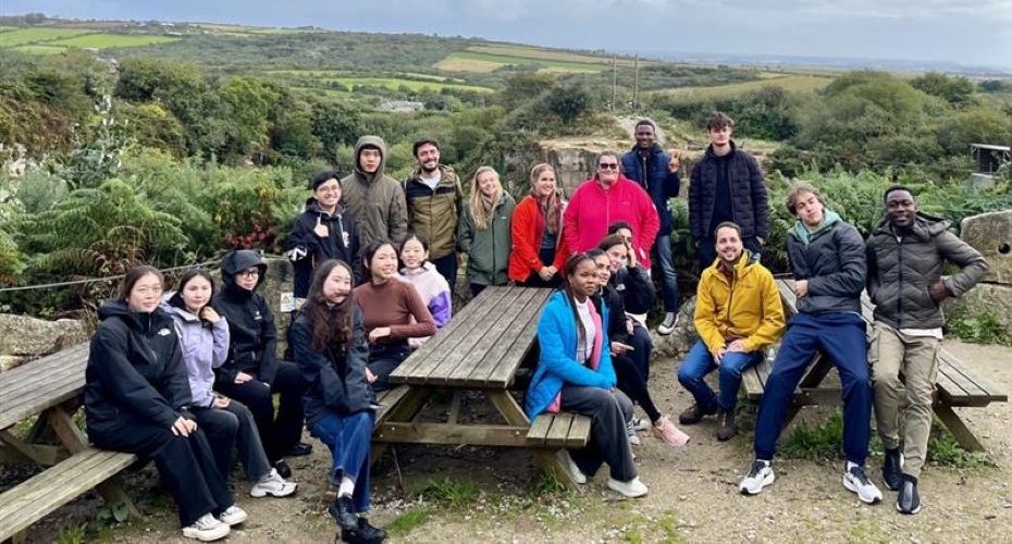 Group of students around a wooden picnic bench in the countryside