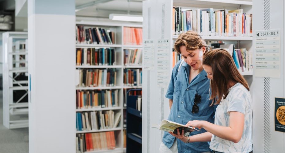 Students looking at a book in a library